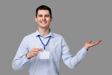 Photo of Smiling man with empty badge showing something on grey background