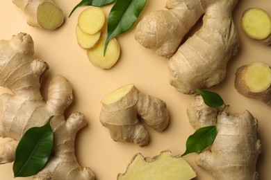 Photo of Fresh ginger with green leaves on beige background, flat lay