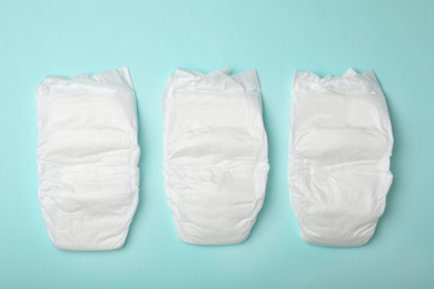 Photo of Baby diapers on turquoise background, flat lay
