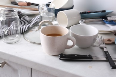 Photo of Many dirty utensils and dishware on countertop in messy kitchen
