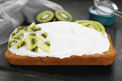Photo of Delicious homemade yogurt cake with kiwi and cream on gray table, closeup