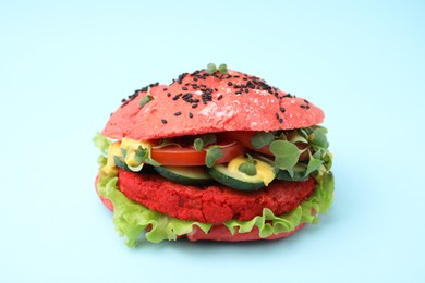 Photo of Tasty pink vegan burger with vegetables, patty and microgreens on light blue background, closeup