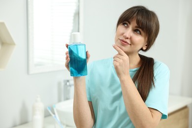 Photo of Young woman with mouthwash in bathroom. Oral hygiene