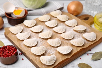 Photo of Raw dumplings (varenyky) with tasty filling and ingredients on white wooden table