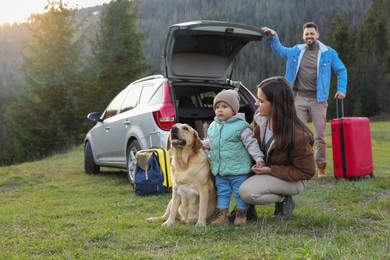 Photo of Mother with her daughter, dog and man near car in mountains. Family traveling with pet