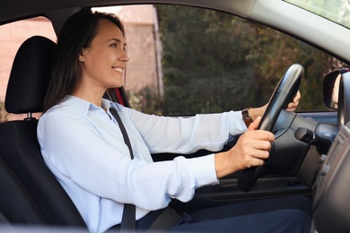 Woman with fastened safety belt on driver's seat in car