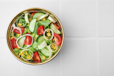 Photo of Bowl of tasty salad with leek, tomatoes and cucumbers on white tiled table, top view. Space for text