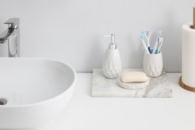 Photo of Different bath accessories and personal care products near sink on bathroom vanity