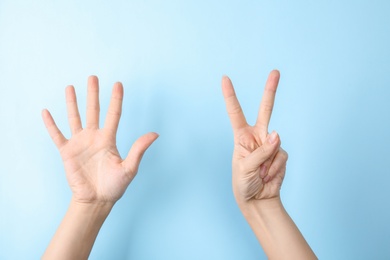 Photo of Woman showing sign seven on color background, closeup. Body language
