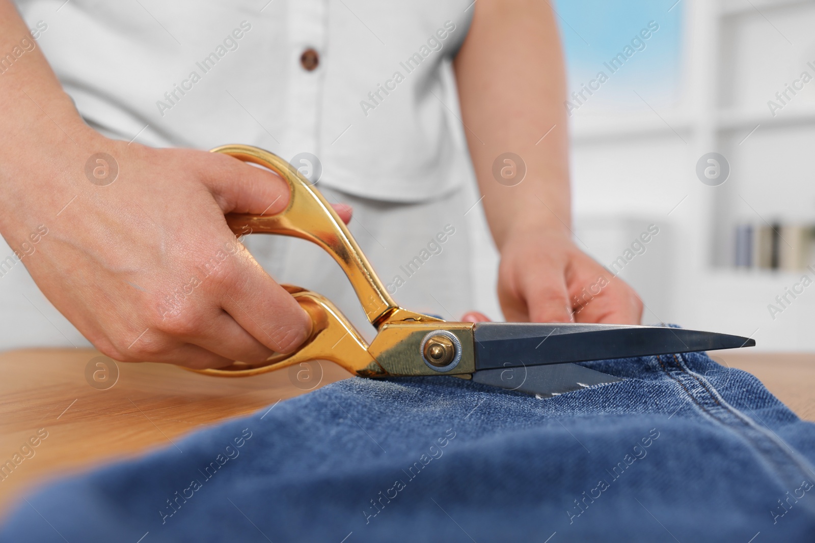 Photo of Woman making ripped jeans at table, closeup