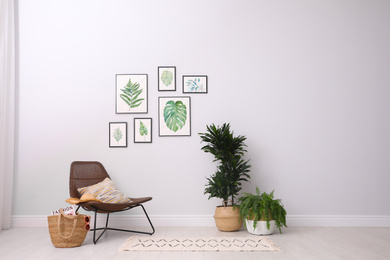 Photo of Beautiful paintings of tropical leaves on white wall in living room interior