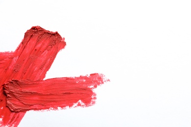 Photo of Red lipstick smear on white background, top view. Space for text