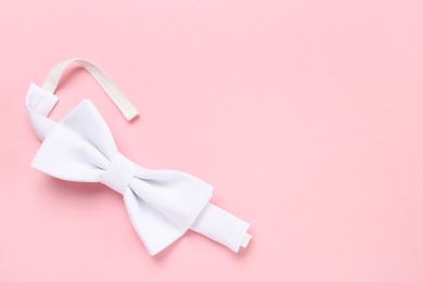 Photo of Stylish white bow tie on pink background, top view. Space for text