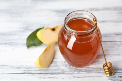 Photo of Jar of honey, apples and dipper on wooden table