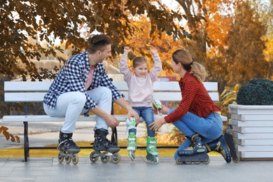 Photo of Happy family wearing roller skates on bench outdoors