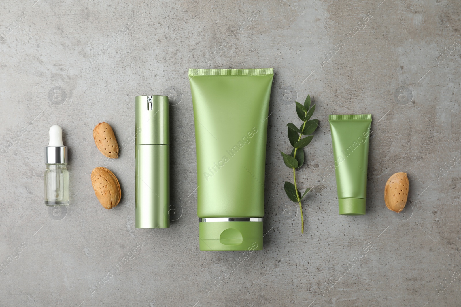 Set of cosmetic products, almond nuts and plant on grey table, flat lay Photo of Set of cosmetic products, almond nuts and plant on grey table, flat lay