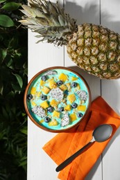 Photo of Delicious smoothie bowl with fresh fruits, blueberries and oatmeal served on white wooden table outdoors, flat lay