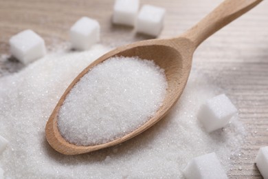 Photo of Different types of white sugar and spoon on table, closeup