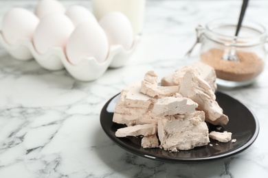Photo of Pieces of compressed yeast on white marble table. Space for text