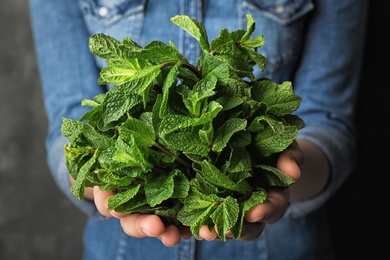 Photo of Young woman holding bunch of fresh mint, closeup