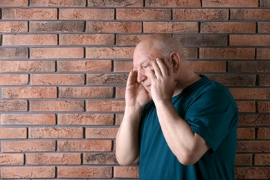 Photo of Senior man in state of depression near brick wall