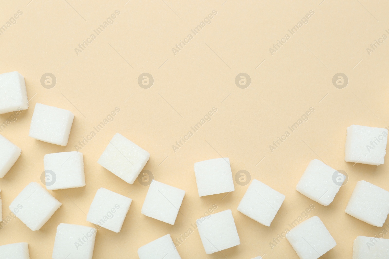 White sugar cubes on beige background, top view. Space for text Photo of White sugar cubes on beige background, top view. Space for text
