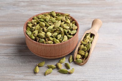 Photo of Bowl and scoop with dry cardamom pods on wooden table