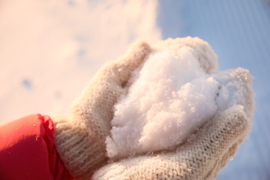 Photo of Woman holding pile of snow outdoors, closeup. Winter vacation