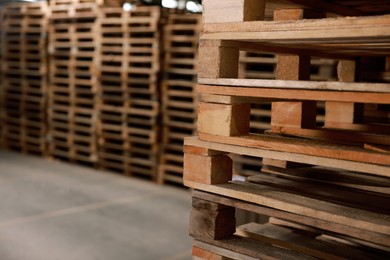 Image of Many empty wooden pallets stacked in warehouse, closeup. Space for text