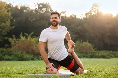 Photo of Man practicing yoga on mat in park