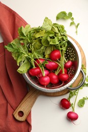 Photo of Wet radish in colander on white table, flat lay