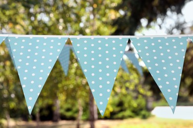 Photo of Light blue bunting flags in park. Party decor