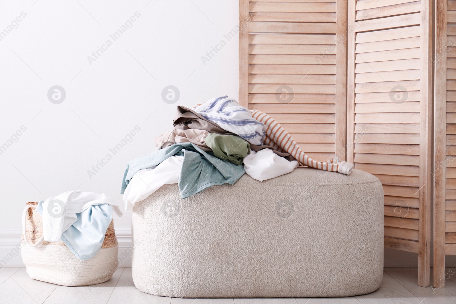 Photo of Messy pile of dirty clothes on ottoman indoors. Tidying up method