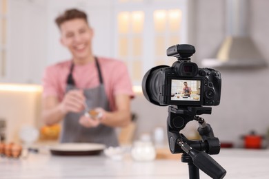 Food blogger recording video in kitchen, focus on camera