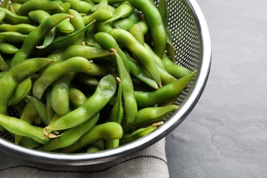 Photo of Sieve with green edamame beans in pods on table, closeup
