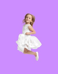 Image of Happy cute girl jumping on violet background