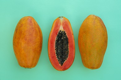 Photo of Fresh ripe papaya fruits on light turquoise background, flat lay