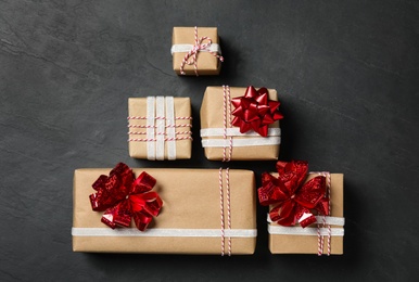 Christmas gift boxes with red bows on dark grey background, flat lay