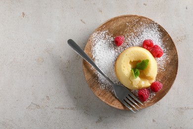 Photo of Tasty vanilla fondant with white chocolate and raspberries on light grey table, top view. Space for text