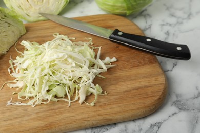 Photo of Chopped ripe cabbage on white marble table, closeup