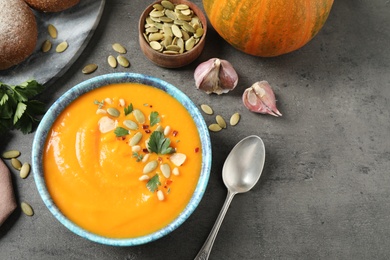 Photo of Delicious pumpkin soup in bowl on grey table, flat lay