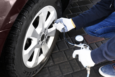 Photo of Mechanic checking tire air pressure at car service, closeup