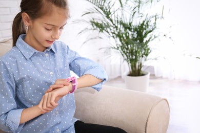 Photo of Girl using stylish smart watch on sofa indoors