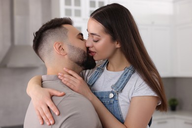 Photo of Affectionate young couple kissing in light kitchen