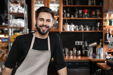 Photo of Portrait of smiling barista in coffee shop. Space for text
