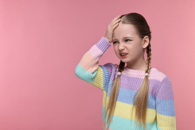 Photo of Little girl suffering from headache on pink background. Space for text