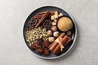 Photo of Plate with different aromatic spices on light textured table, top view