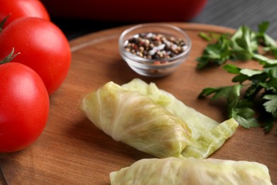 Photo of Uncooked stuffed cabbage rolls on wooden board, closeup
