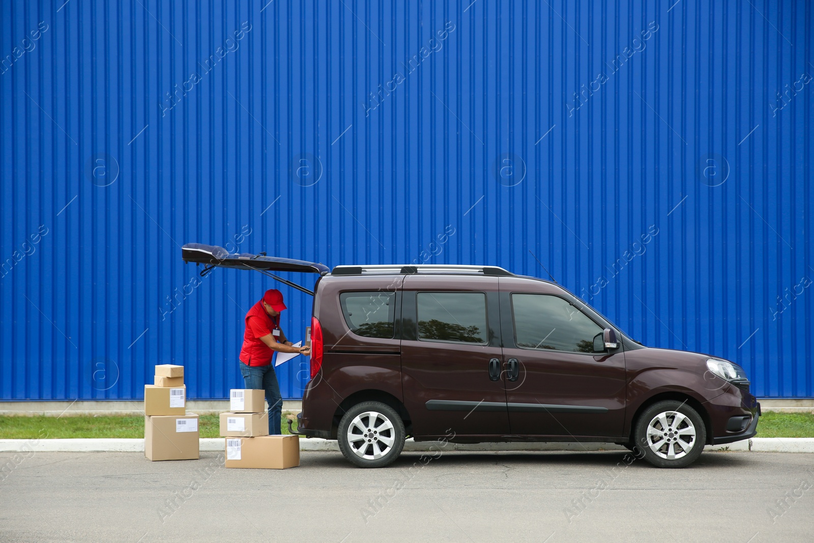 Photo of Courier loading packages in car outdoors, space for text