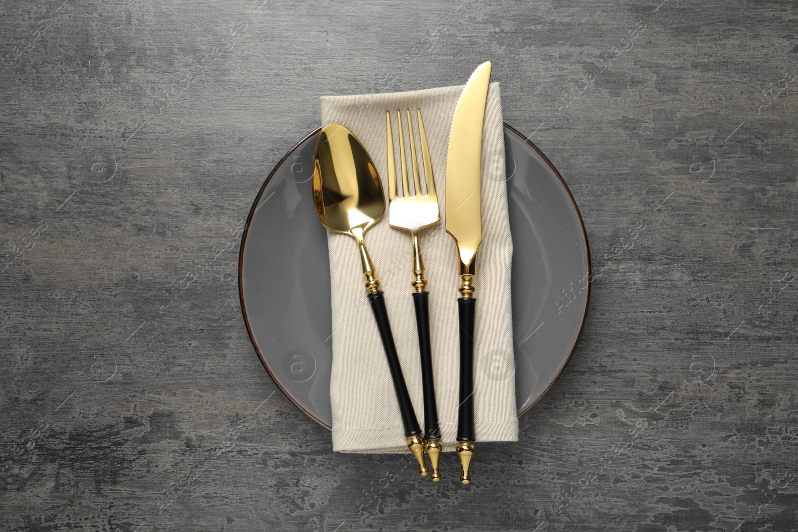 Elegant setting with golden cutlery on dark grey table, top view Photo of Elegant setting with golden cutlery on dark grey table, top view